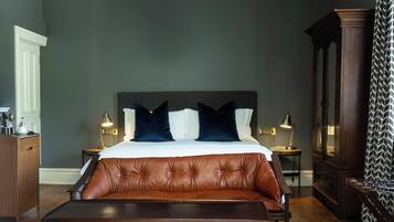 A bedroom with a large bed, a bench, a wooden cabinet, and a ceiling light fixture.