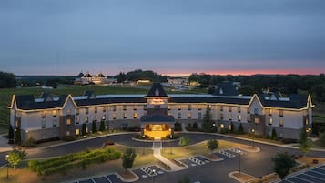 A large, multi-story hotel with a central entrance, parking lot, and landscaped areas.