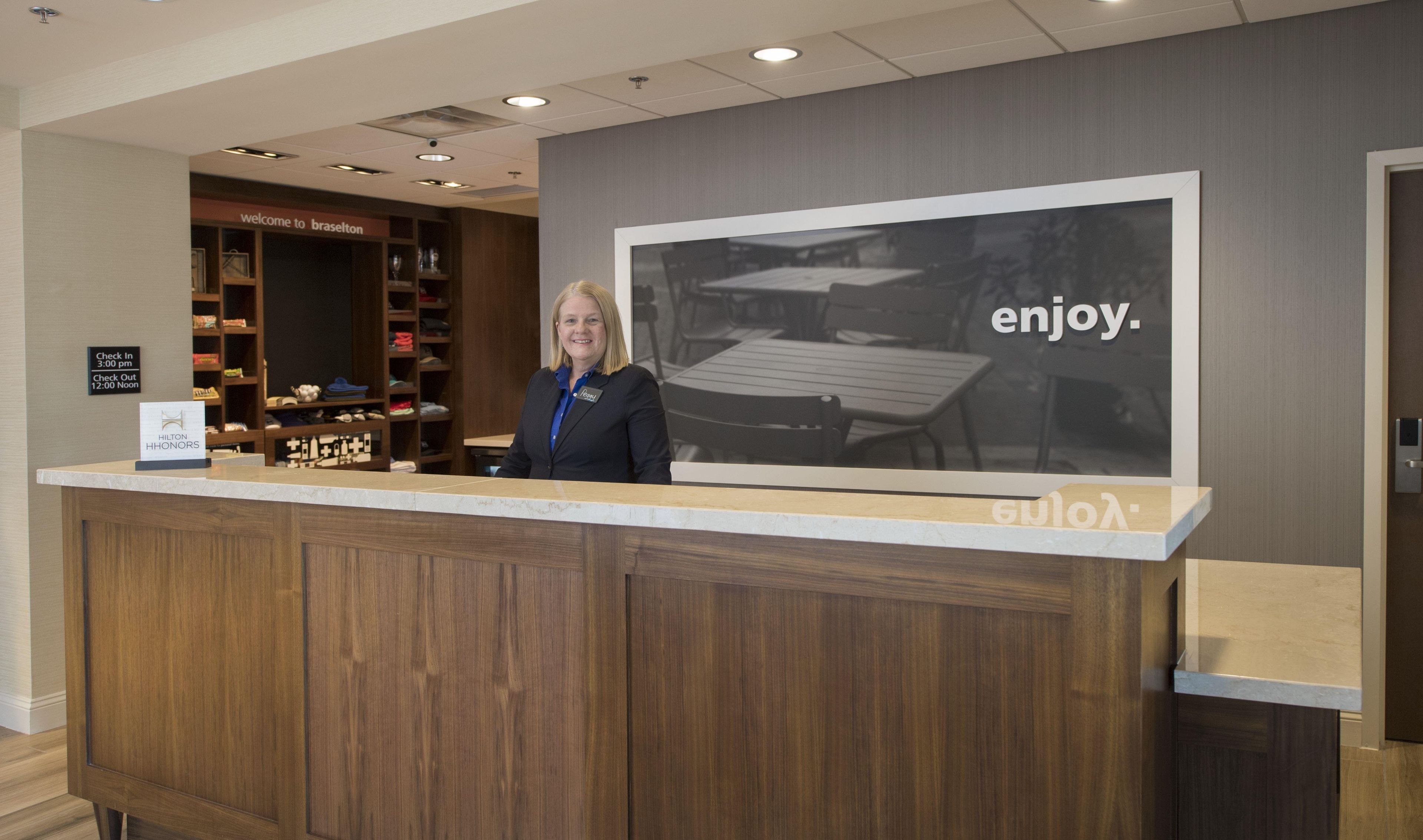 A hotel reception desk with a large welcome sign and a framed photo of a dining area.