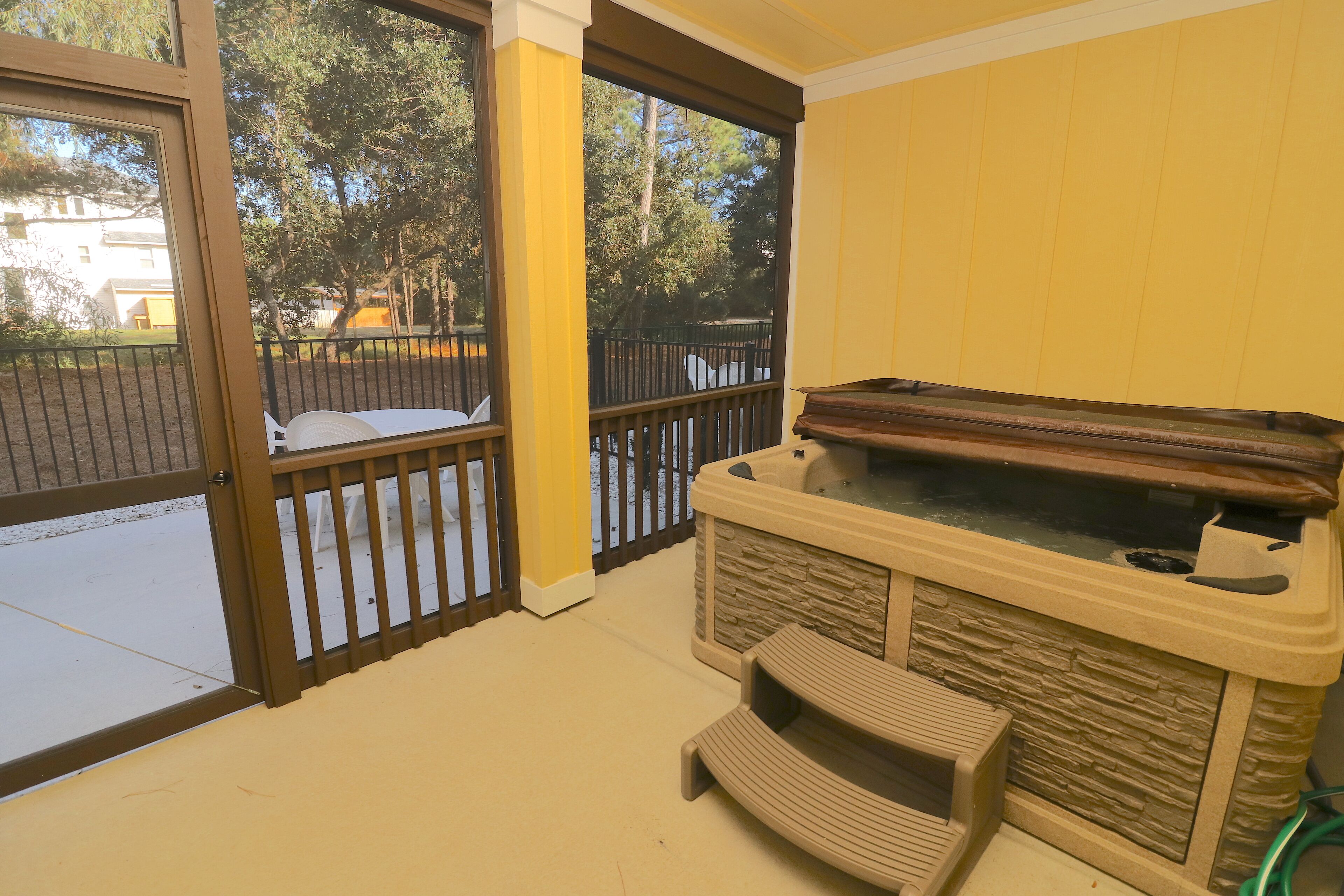 A room with a stone fireplace, a bench, and a view of a fenced outdoor area.