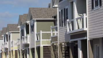 A row of townhouses with front porches, a garage, and a clear sky.