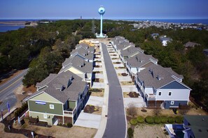Un quartier résidentiel composé d’une rangée de maisons, d’une rue principale et, au loin, d’un château d’eau.