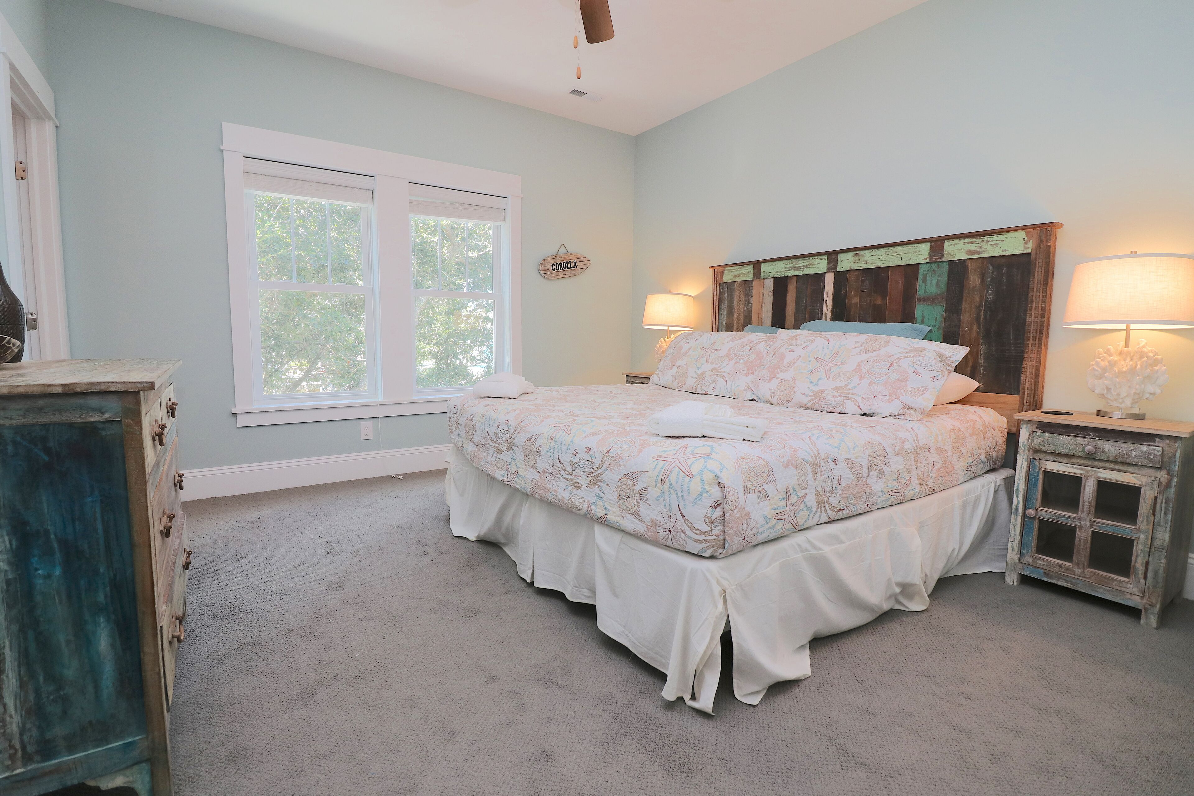 A bedroom with a bed, a window, a nightstand, and a dresser.