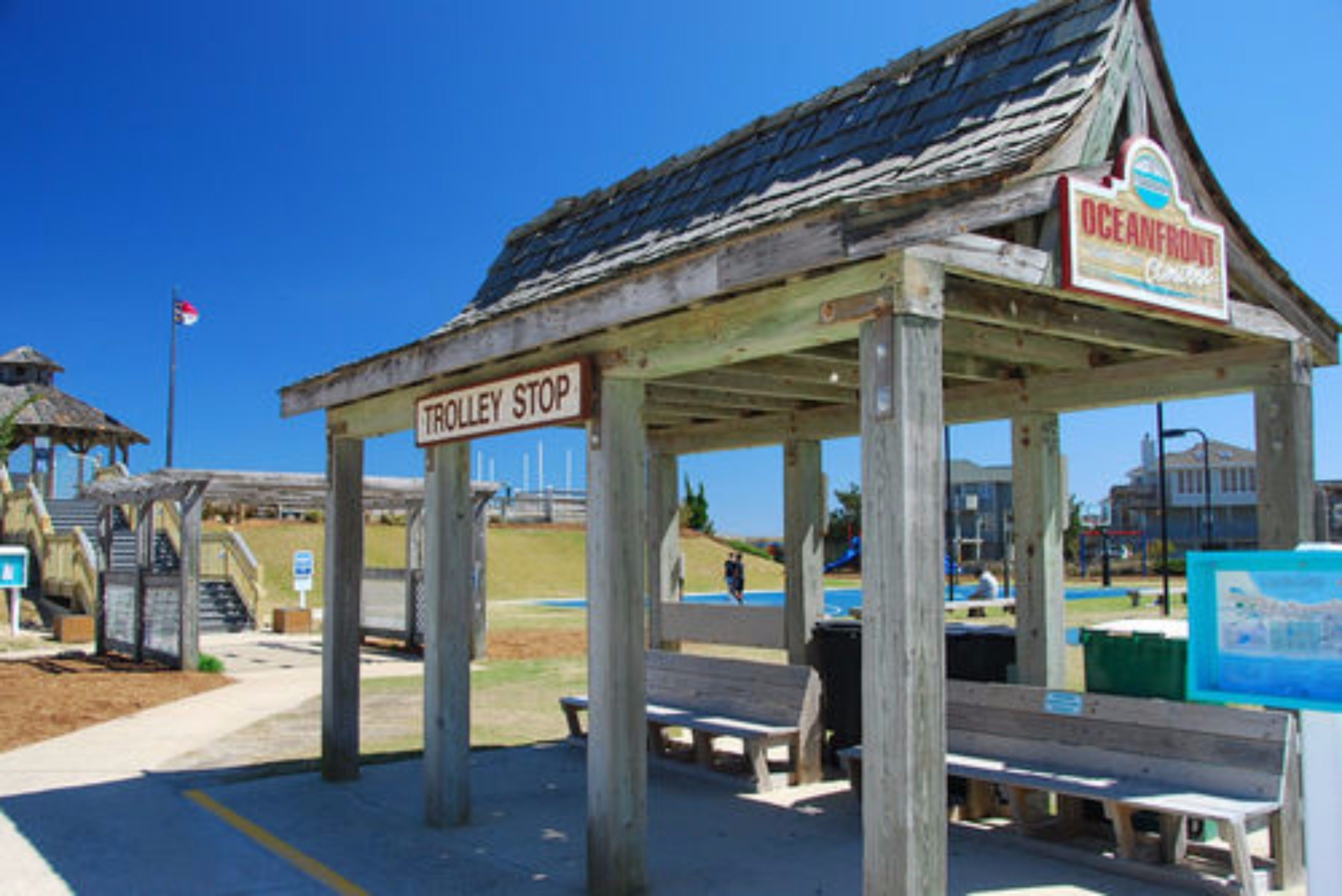 A wooden structure labeled 'TROLLEY STOP' with a sign for 'OCEANFRONT' and benches.