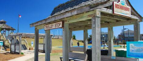 A wooden structure labeled 'TROLLEY STOP' with a sign for 'OCEANFRONT' and benches.