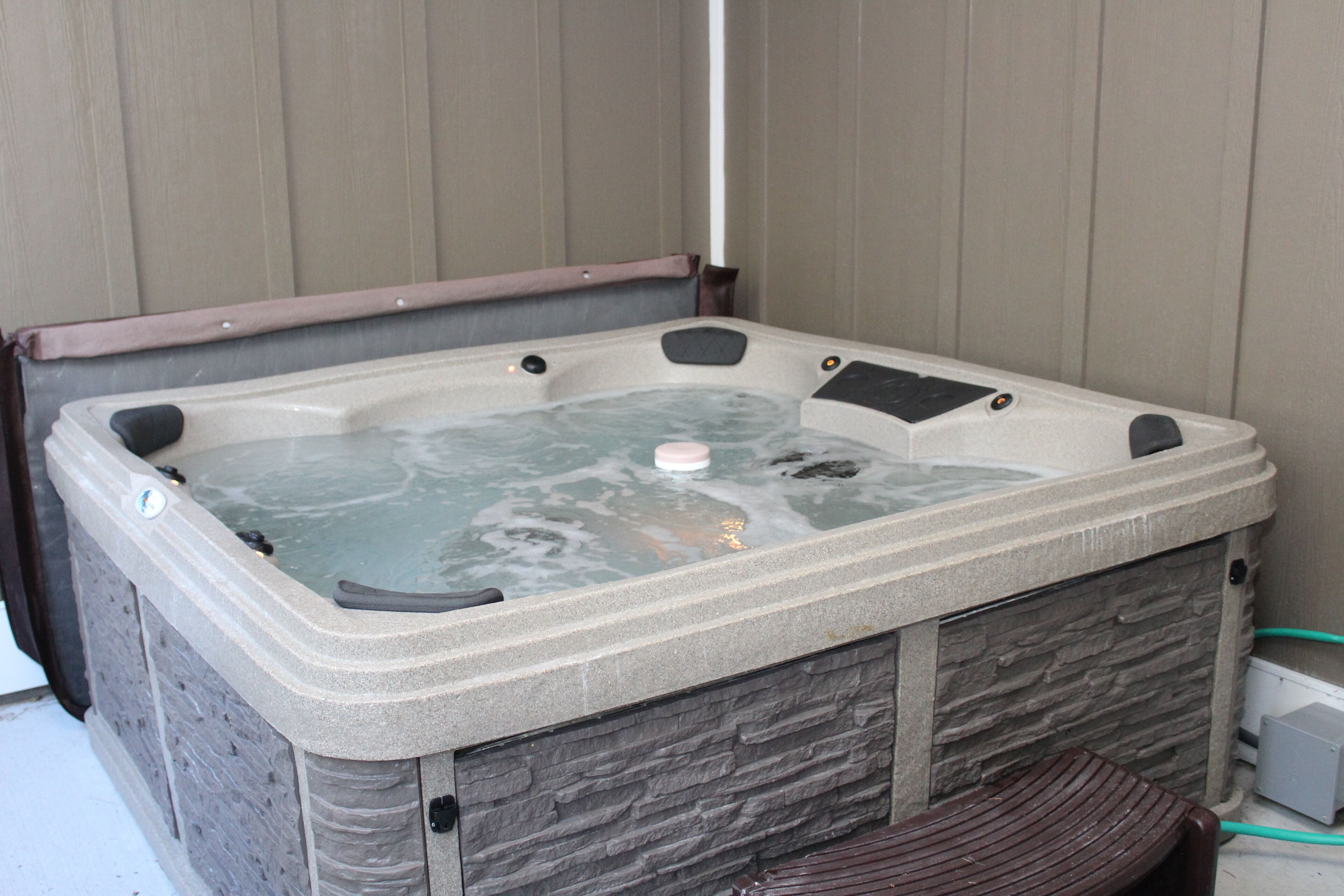 Un jacuzzi con revestimiento de piedra y un banco de madera.