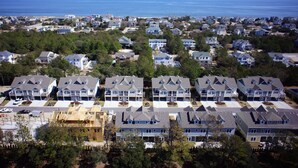 A residential area with multiple two-story houses, some with attached garages, and a clear view of the ocean in the background.