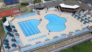 A large outdoor swimming pool with multiple lanes, surrounded by sun loungers and umbrellas.