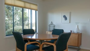 A dining area with a round table and four chairs, a birdcage, a vase, and a framed artwork on the wall. - Riesling Country Cottages (Polish Hill River)
