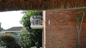 A wooden deck leading to a pool with a thatched roof overhead. - Bluewater Beach Accommodation (Gqeberha (Port Elizabeth))