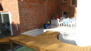 A wooden deck with a pool, a brick wall, and a table with chairs. - Bluewater Beach Accommodation (Gqeberha (Port Elizabeth))