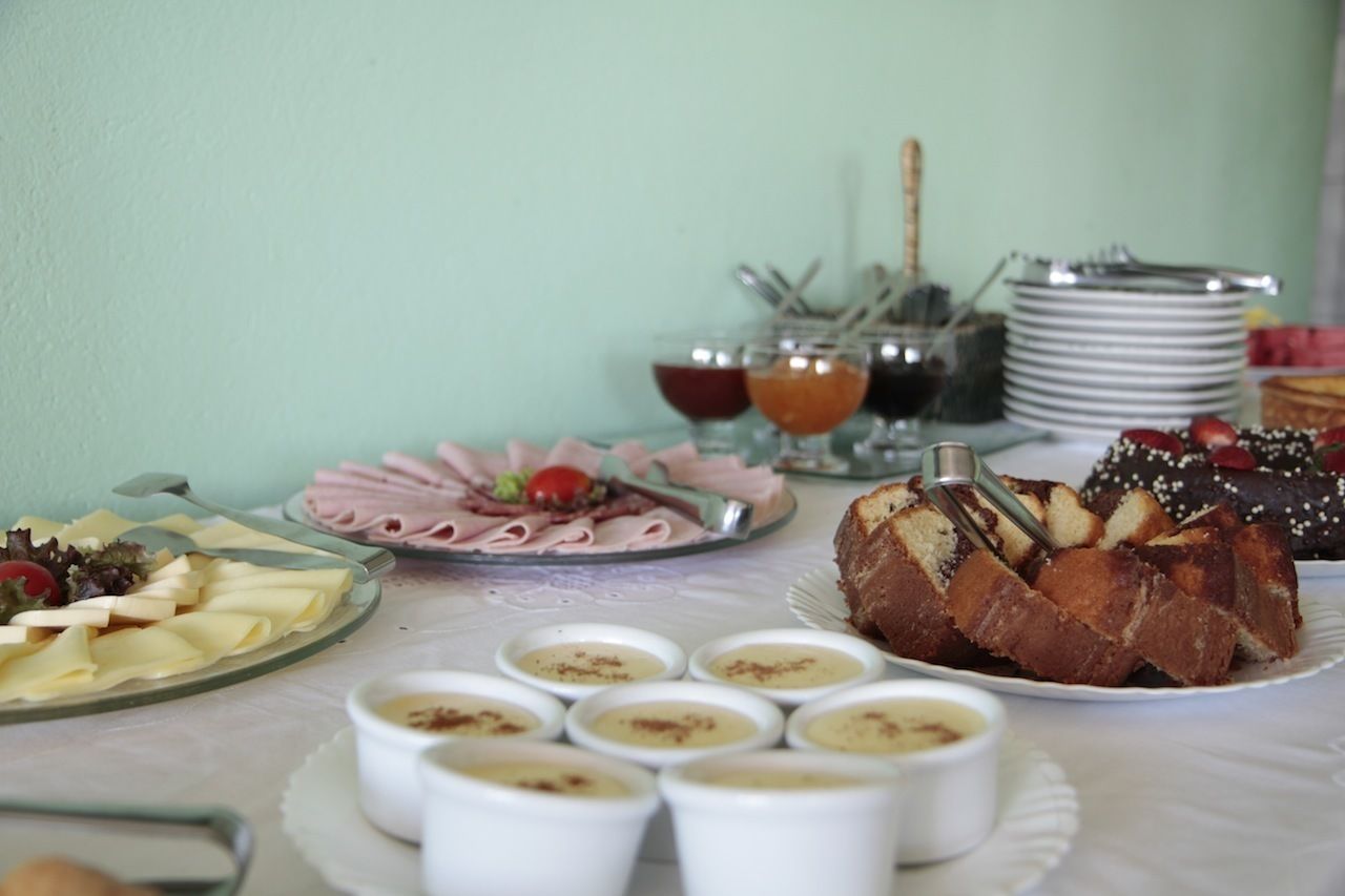 A buffet table with various food items including a cake, cheese, and small bowls of dips.