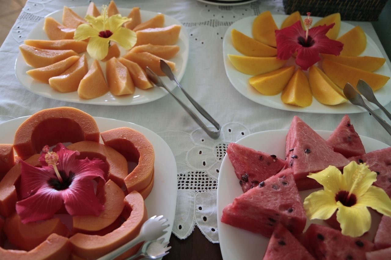 A table with plates of fruit arranged in a circular pattern, each with a flower in the center.