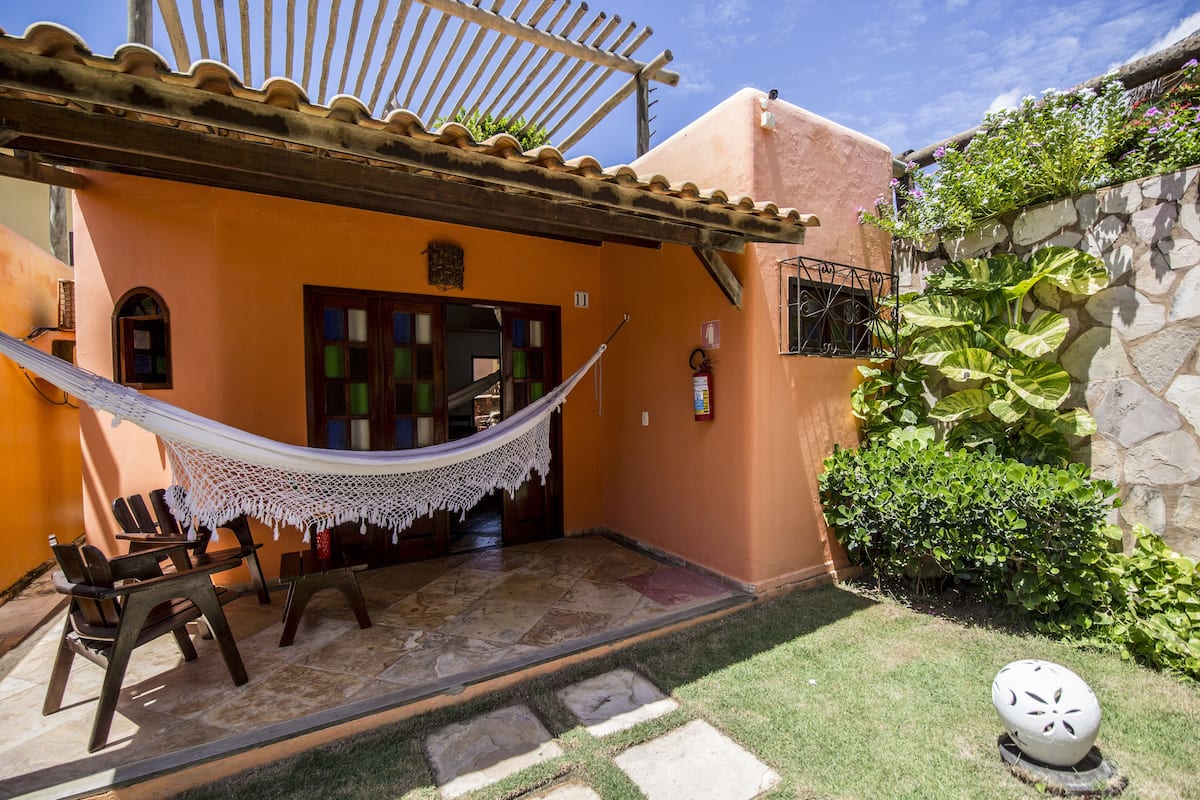A patio with a hammock, outdoor seating, and a stone wall with greenery.