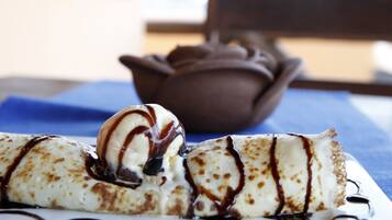 Un plato de postre con un crepe y helado, bañado en salsa de chocolate.