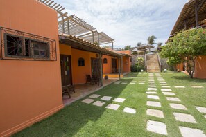 Un patio con un sendero pavimentado, una pérgola y una pequeña zona de estar con sillas.