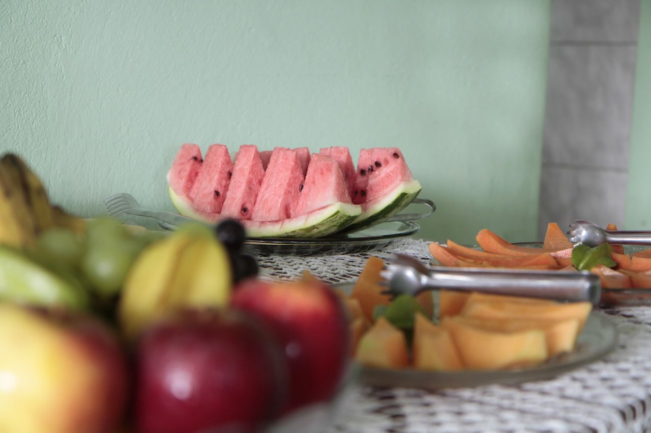 A table with sliced watermelon, apples, and cantaloupe.