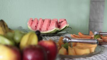 A table with sliced watermelon, apples, and cantaloupe.