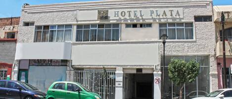 A building with a sign reading "HOTEL PLAZA" and a no parking sign.