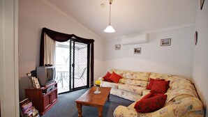A living room with a sofa, a coffee table, a TV, and a bookshelf. - Serenity Grove (Fordwich)
