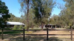 A fenced outdoor area with a building and a covered structure, surrounded by trees. - Serenity Grove (Fordwich)