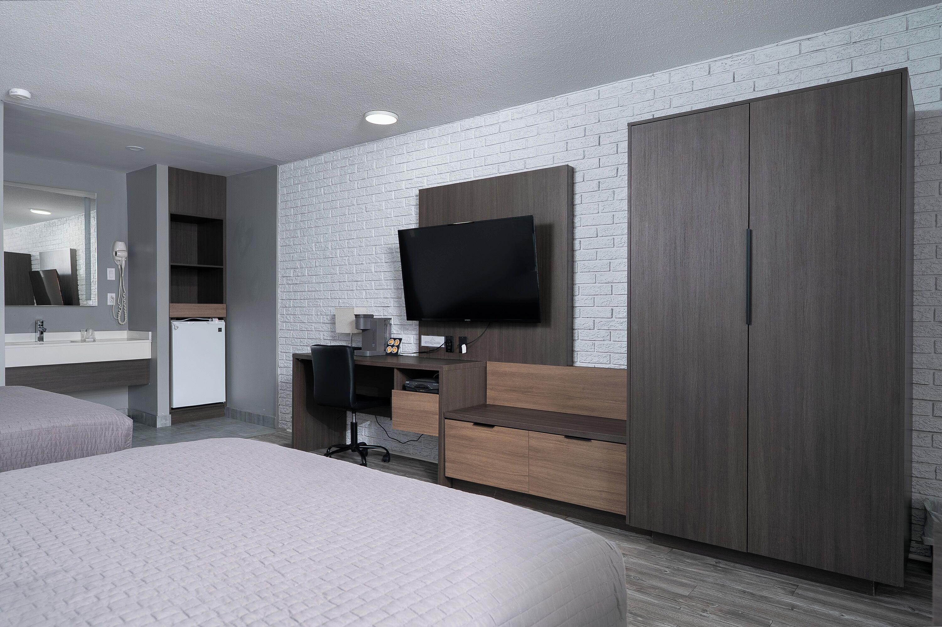Une chambre d’hôtel moderne dotée d’un grand lit, d’un bureau avec une chaise, d’un téléviseur fixé au mur et d’une armoire.