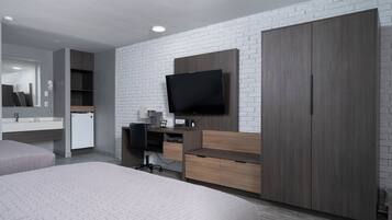 Una habitación de hotel moderna con una cama grande, un escritorio con una silla, un televisor montado en la pared y un armario.
