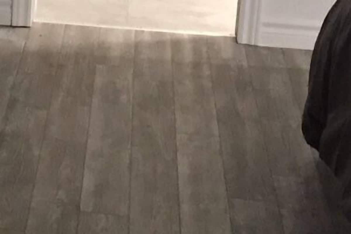 Una habitación con piso de madera, una cama y una puerta.