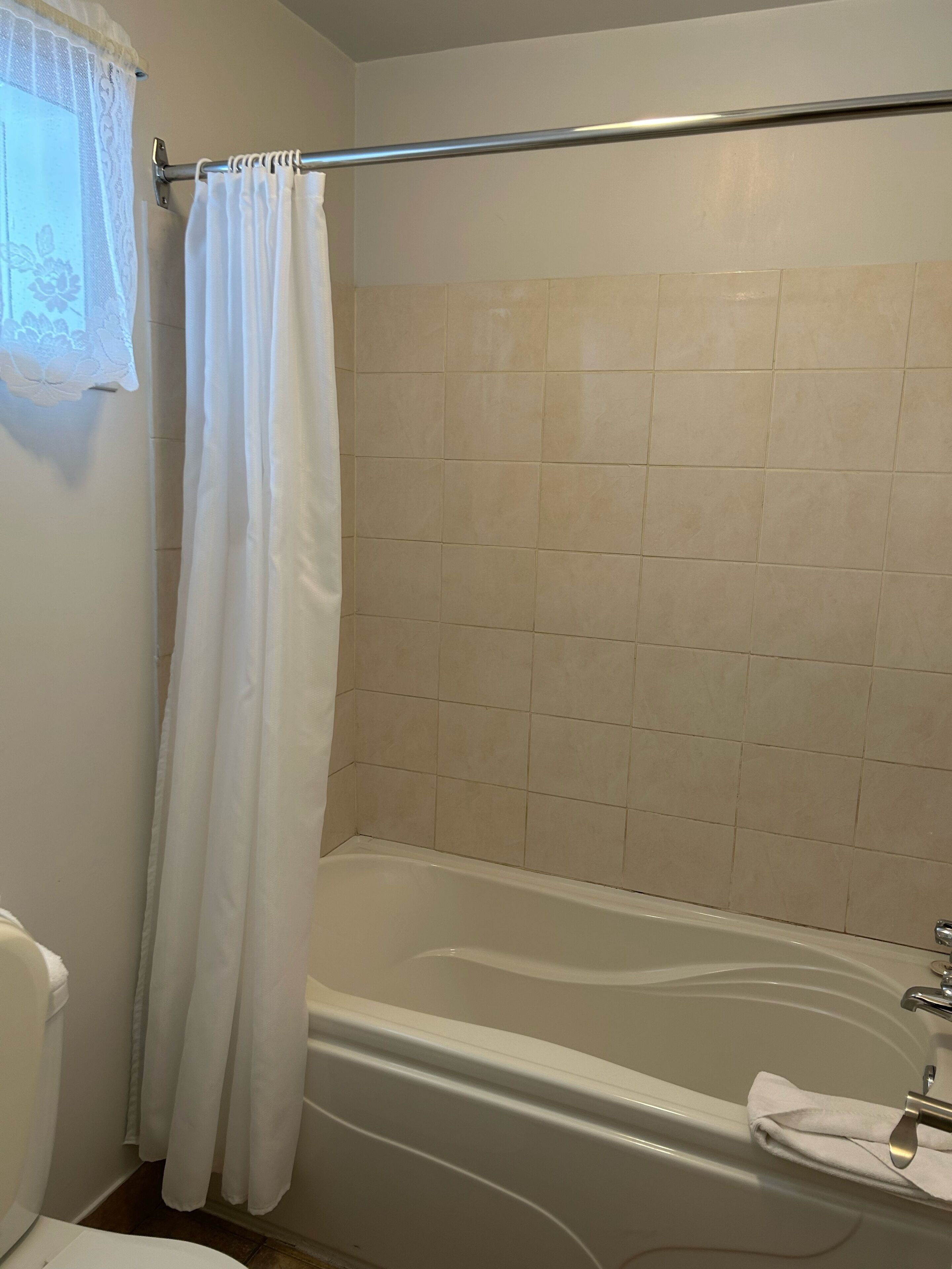 Un baño con bañera, cortina de ducha y paredes con azulejos.