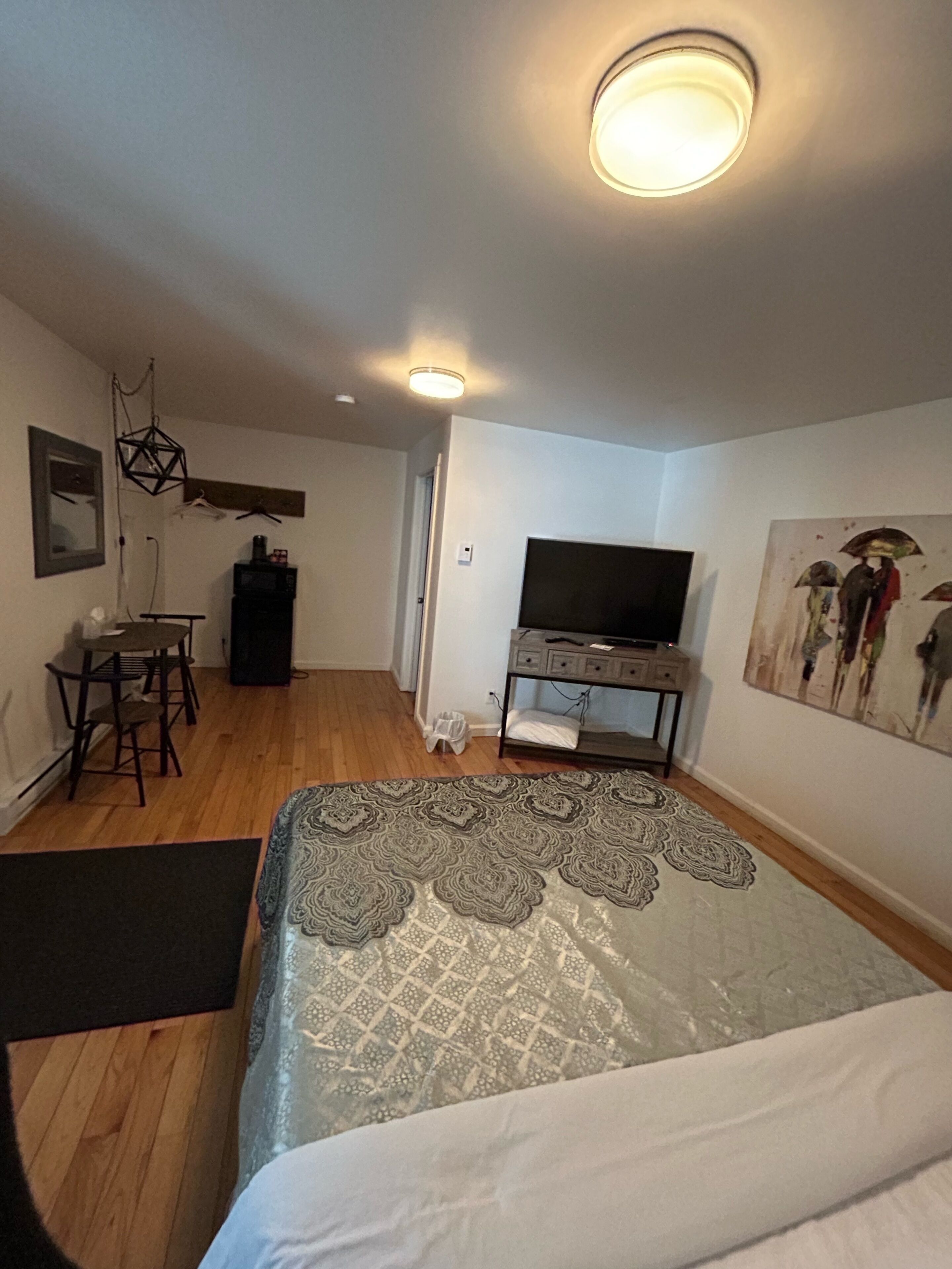 Une chambre d’hôtel avec un lit, un bureau, une télévision et un tableau au mur.