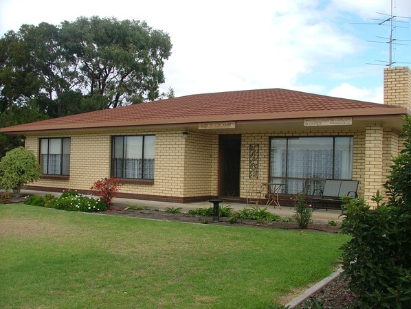 A two-story house with a brick exterior, a tiled roof, and a front porch with a table and chairs. - Kirazz (Kingscote)