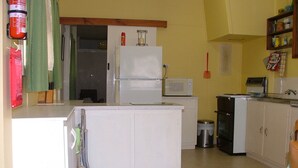 Une cuisine compacte équipée d’un réfrigérateur, d’un four à micro-ondes et d’une petite poubelle.