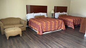 A hotel room with two beds, a sofa, and a nightstand. - Riviera Inn & Suites (Riviera)