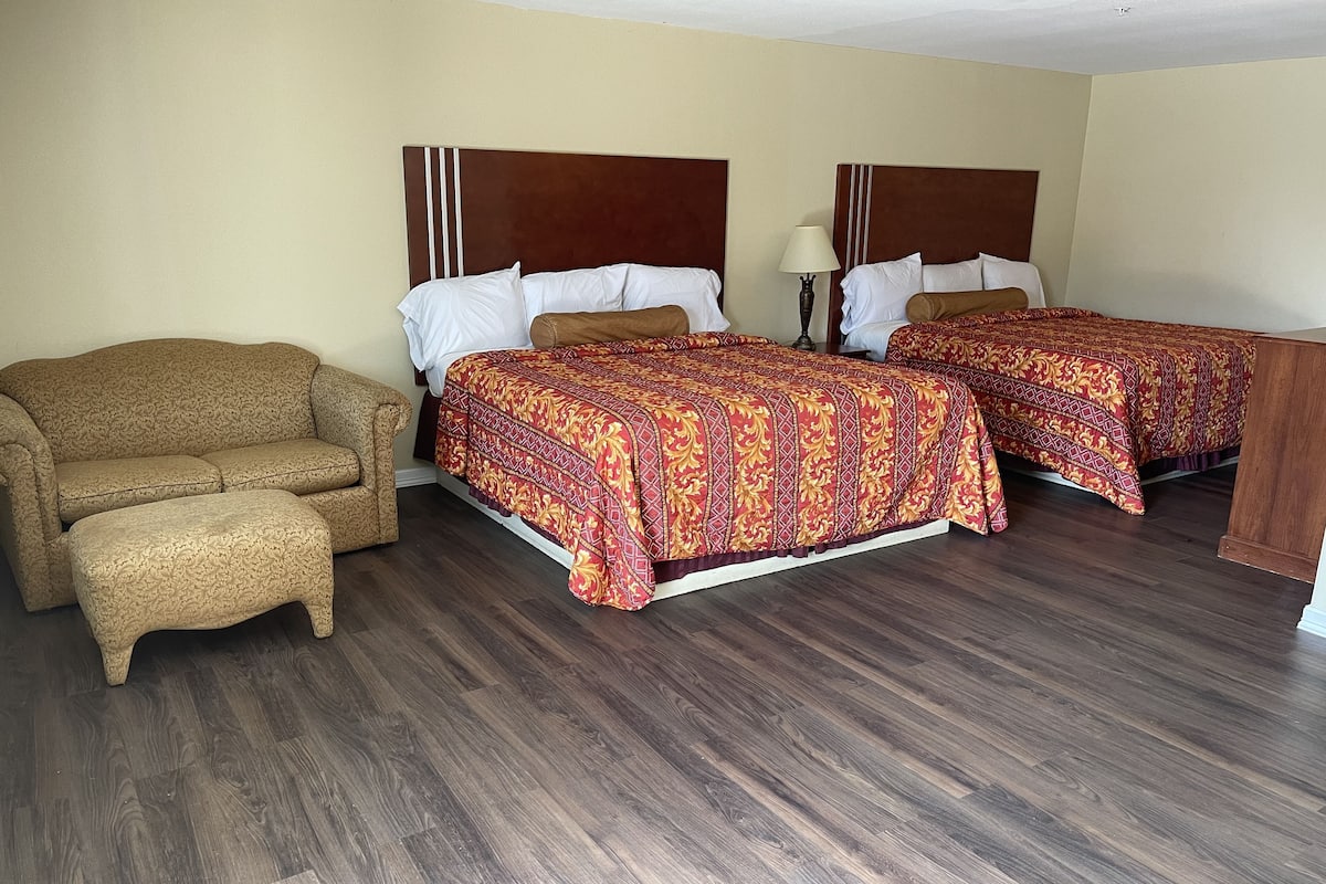 A hotel room with two beds, a sofa, and a nightstand.