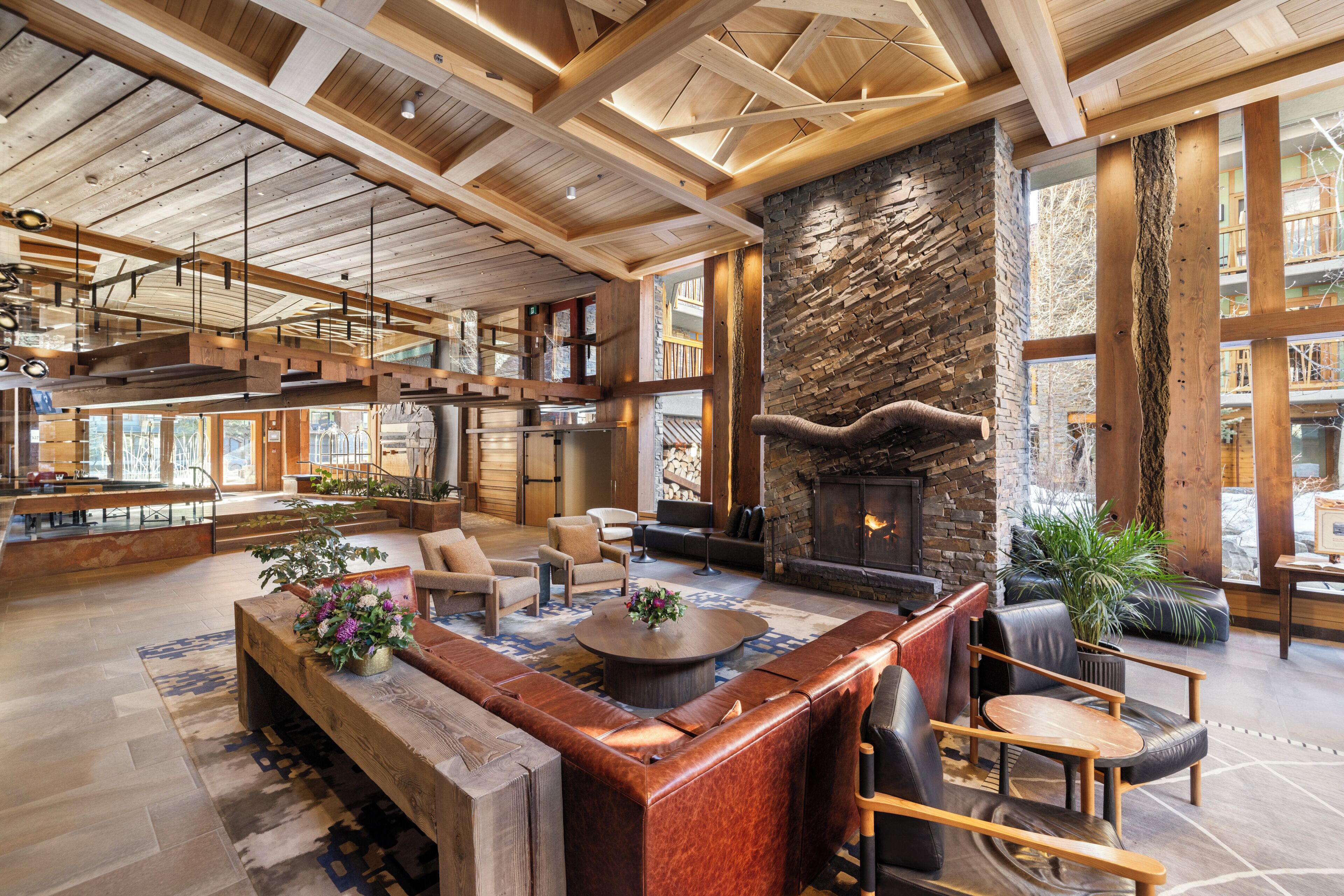 A spacious lobby with a stone fireplace, wooden ceiling beams, and a seating area with leather sofas.
