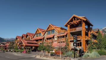 A row of wooden cabins with balconies, set against a mountainous backdrop.