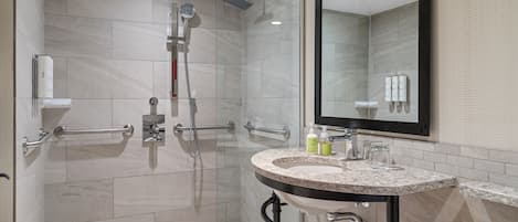 A modern bathroom with a glass-enclosed shower, a vanity with a sink, and a large mirror.