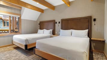A hotel room with two beds, wooden beams on the ceiling, a window with a view, and a carpeted floor.