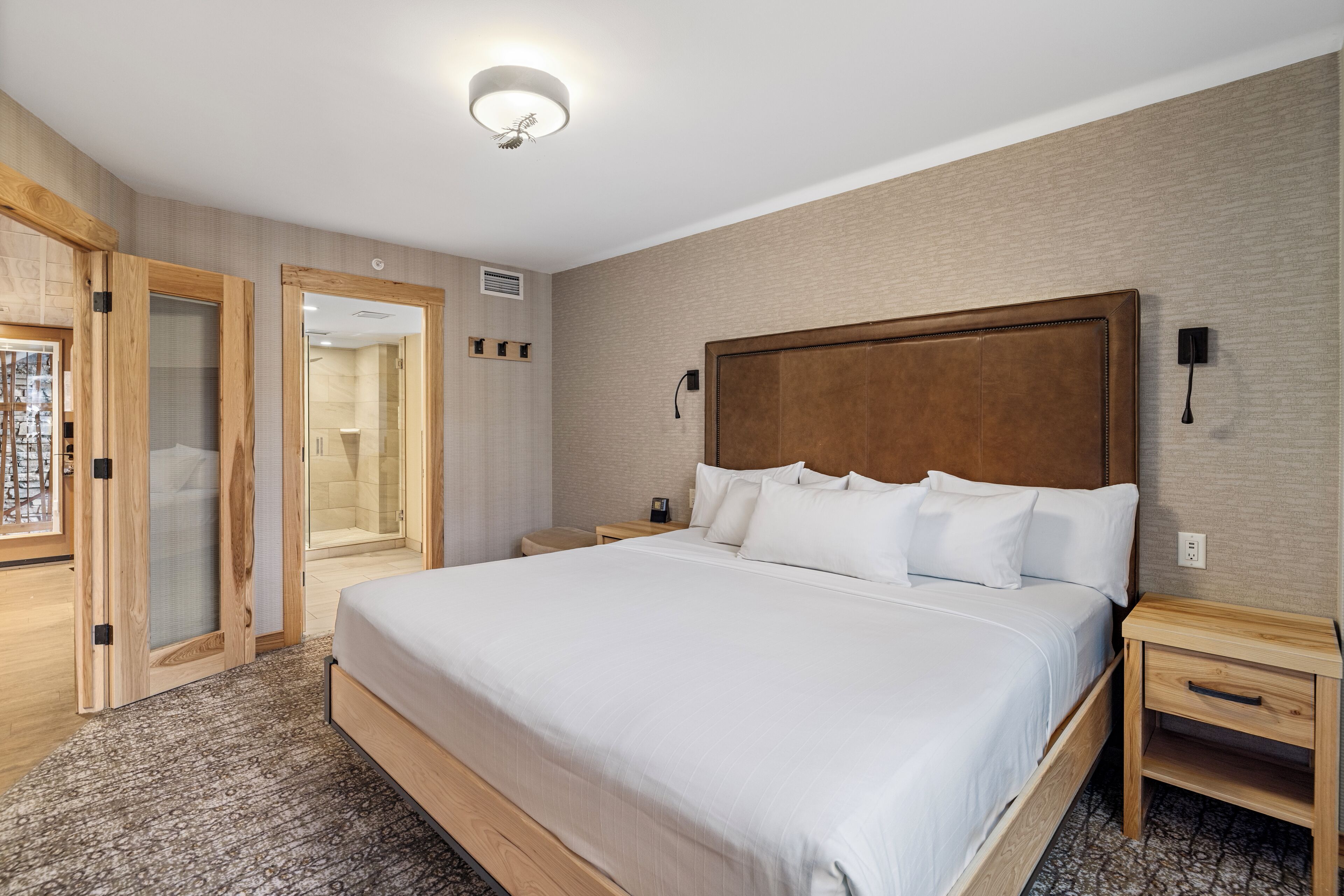 A hotel room with a large bed, wooden headboard, bedside tables, and a walk-in closet.