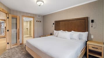 A hotel room with a large bed, wooden headboard, bedside tables, and a walk-in closet.