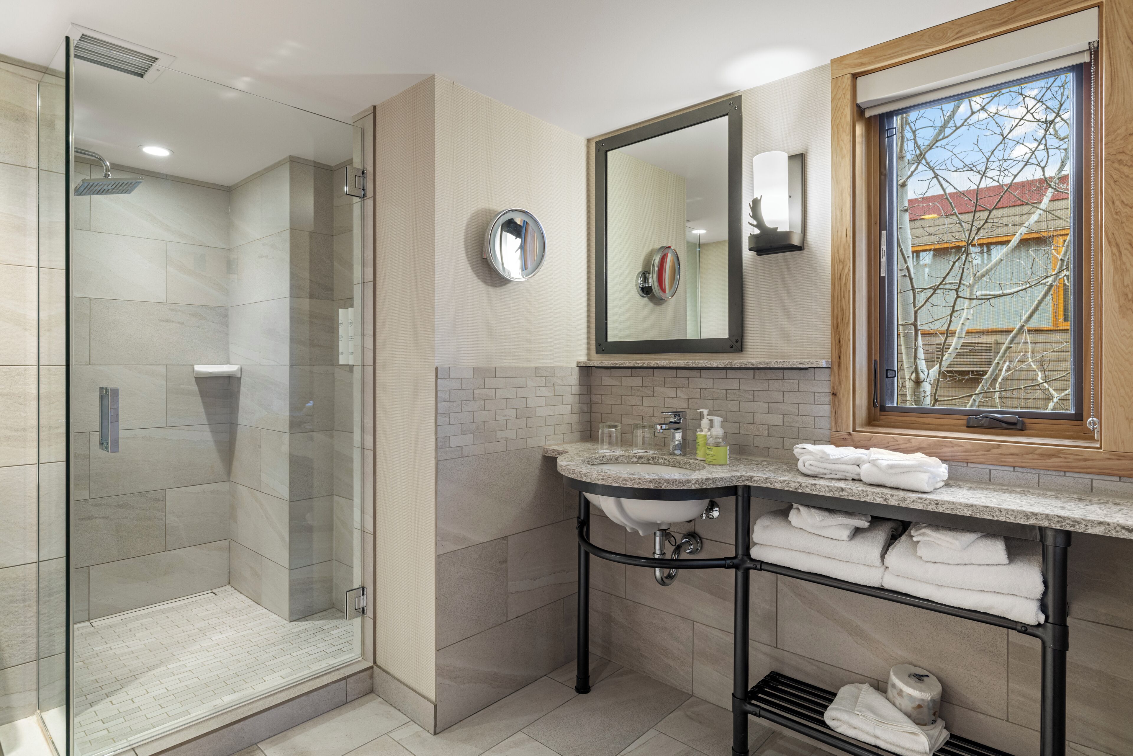 Un baño moderno con cabina de ducha de vidrio, un lavabo con tocador y una ventana con vistas al exterior.