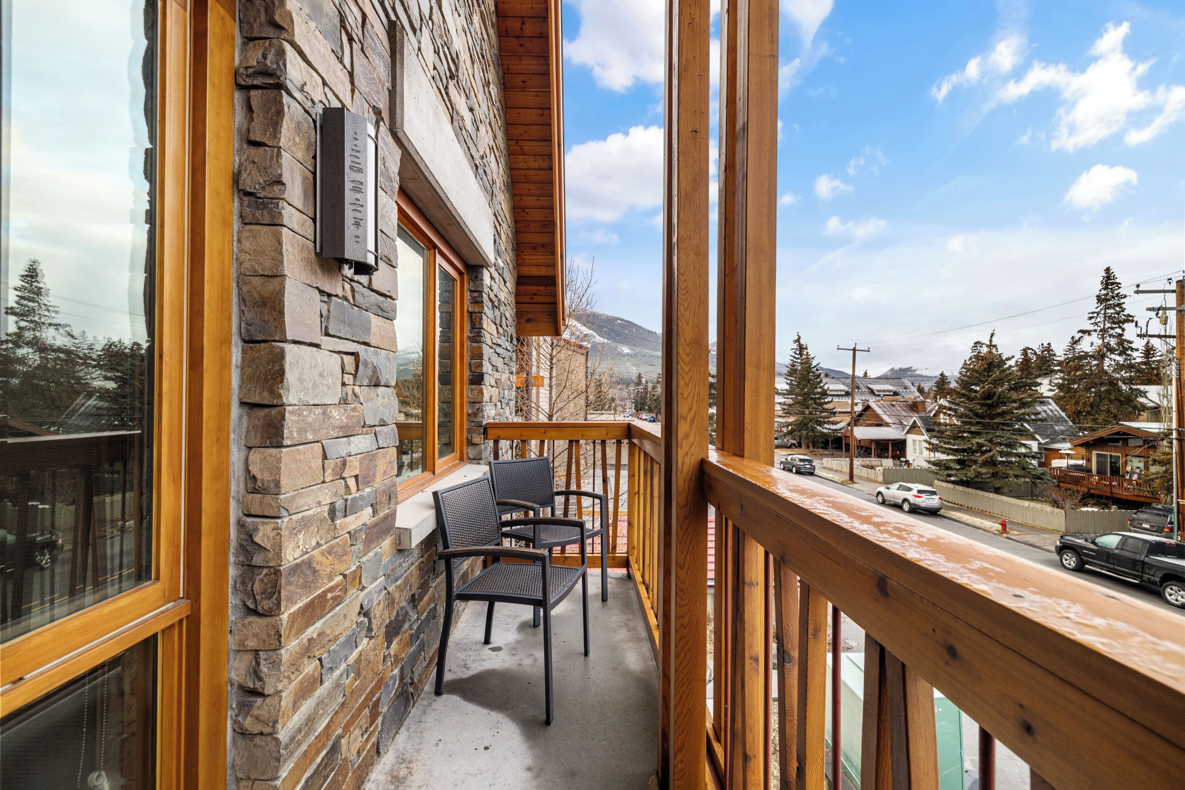 Ein Balkon mit Steinmauern, Holzgeländern und Blick auf eine verschneite Landschaft mit Häusern.