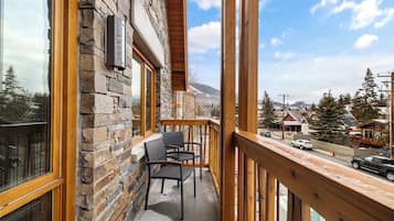 Ein Balkon mit Steinmauern, Holzgeländern und Blick auf eine verschneite Landschaft mit Häusern.