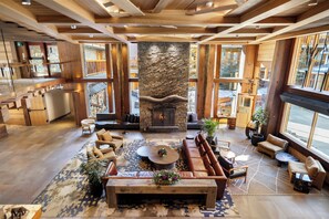 A spacious lounge area with a stone fireplace, comfortable seating, and large windows. - Moose Hotel And Suites (Banff)