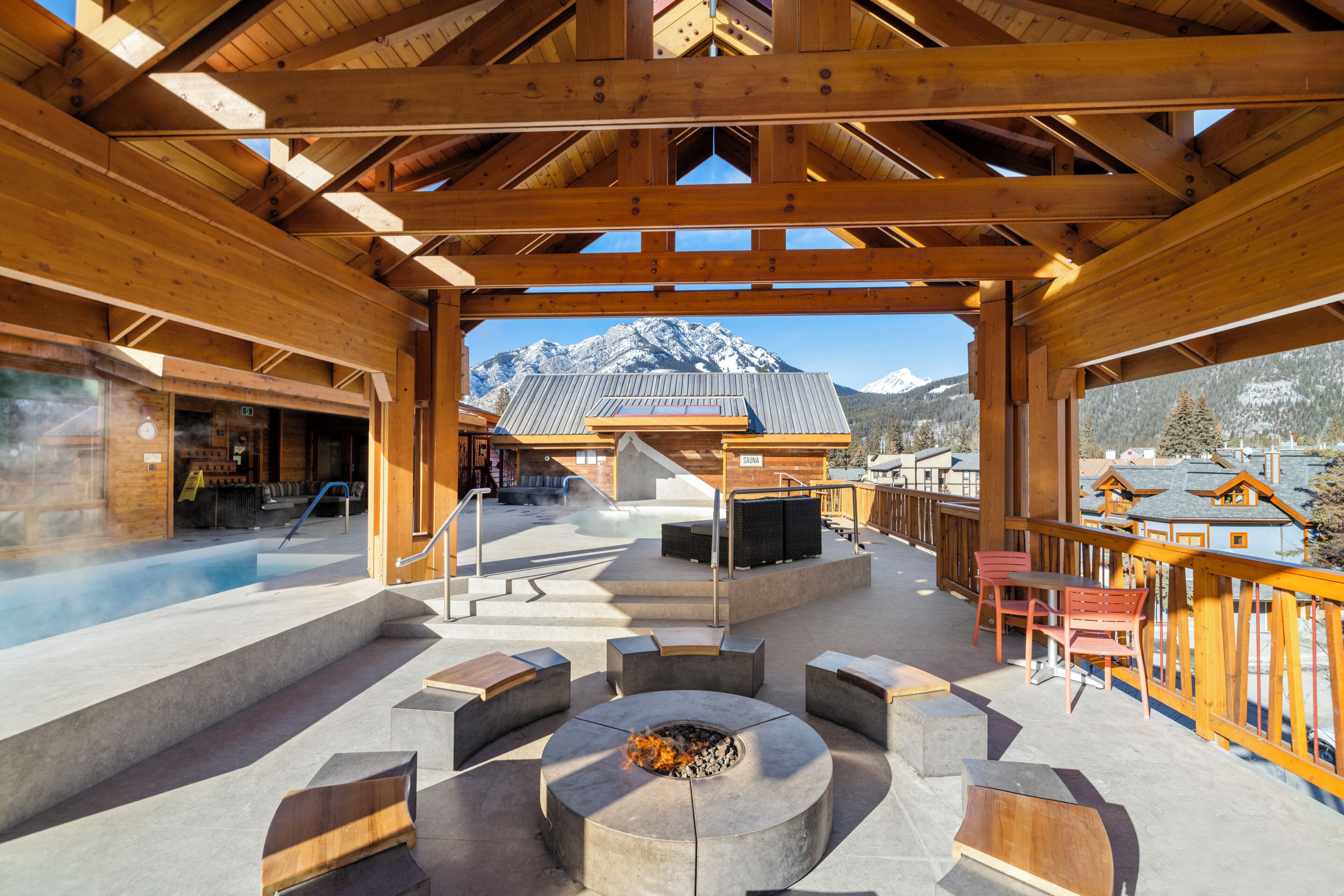 Une terrasse en bois avec un foyer, des sièges d’extérieur et une vue sur des montagnes enneigées.