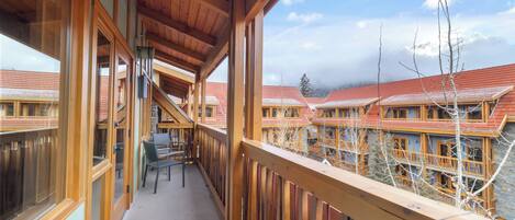 A wooden balcony with a view of a row of buildings with red roofs.