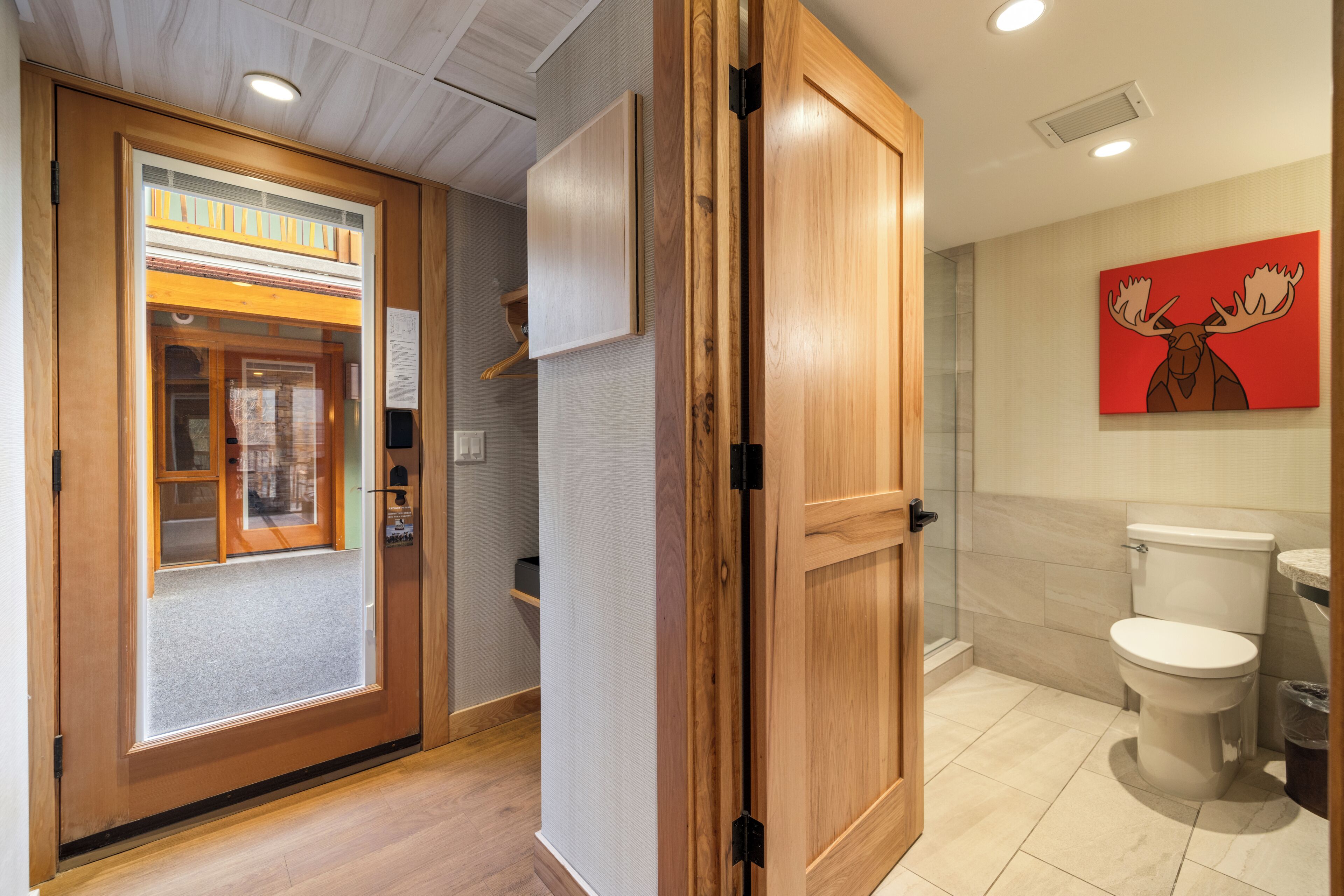 A hotel room with a wooden door, a shower area, and a toilet.