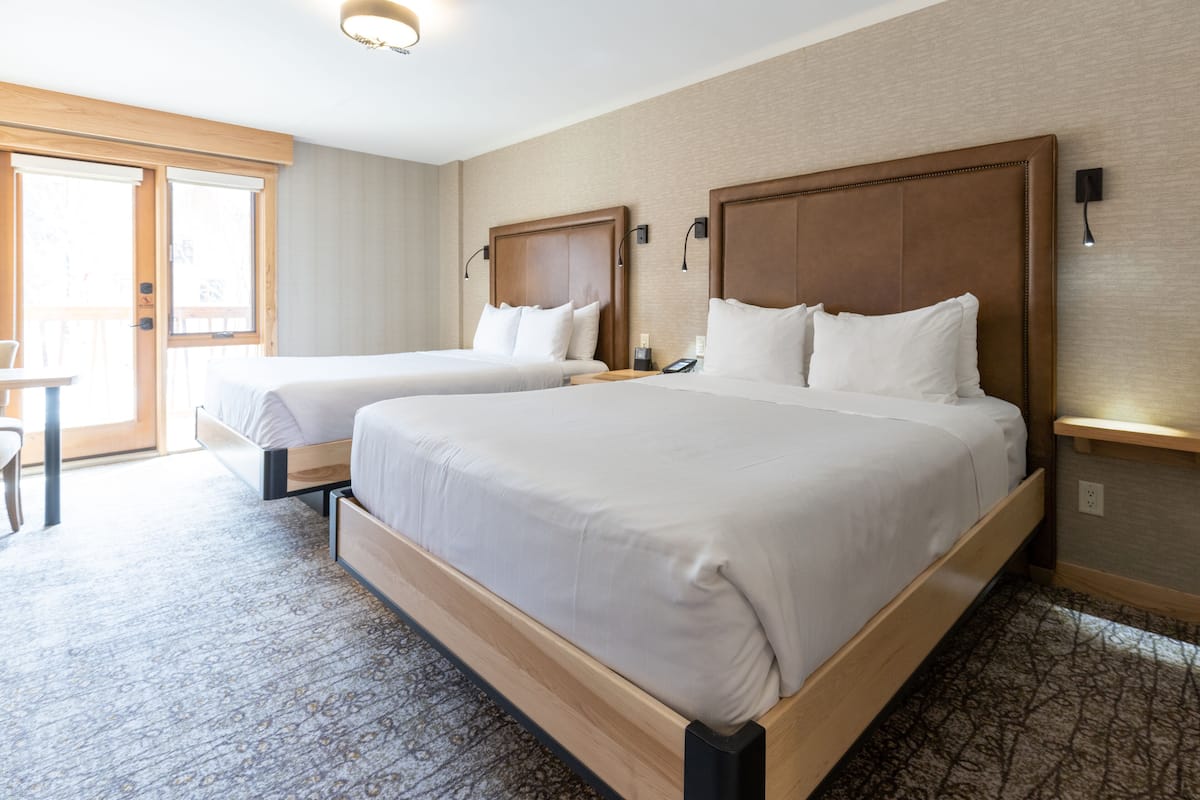 Une chambre d’hôtel avec deux lits, un bureau et une grande fenêtre.