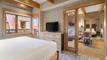 A bedroom with a bed, a television, a desk, and a chair.