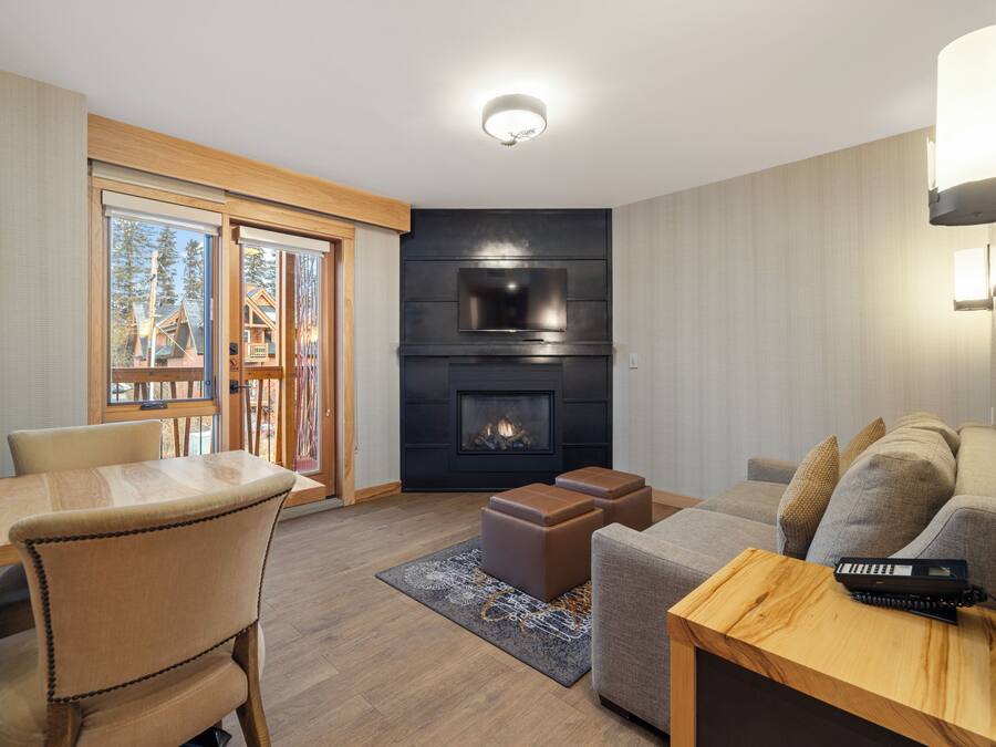 A modern living room with a fireplace, a dining area, and a sofa.